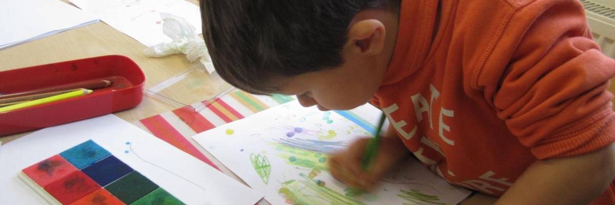 Ein Junge mal mit Stiften und Fingerabdruck ein Bild.