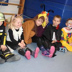 Kinder sitzen in verschiedenen Kostümen da
