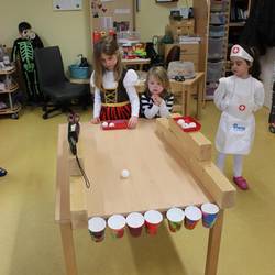 Kinder versuchen Tischtennisbälle in einen Pappbecher rollen