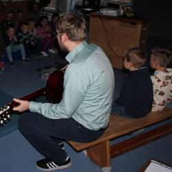 Pastor Jens Wening spielt mit der Gitarre ein Nikolauslied.